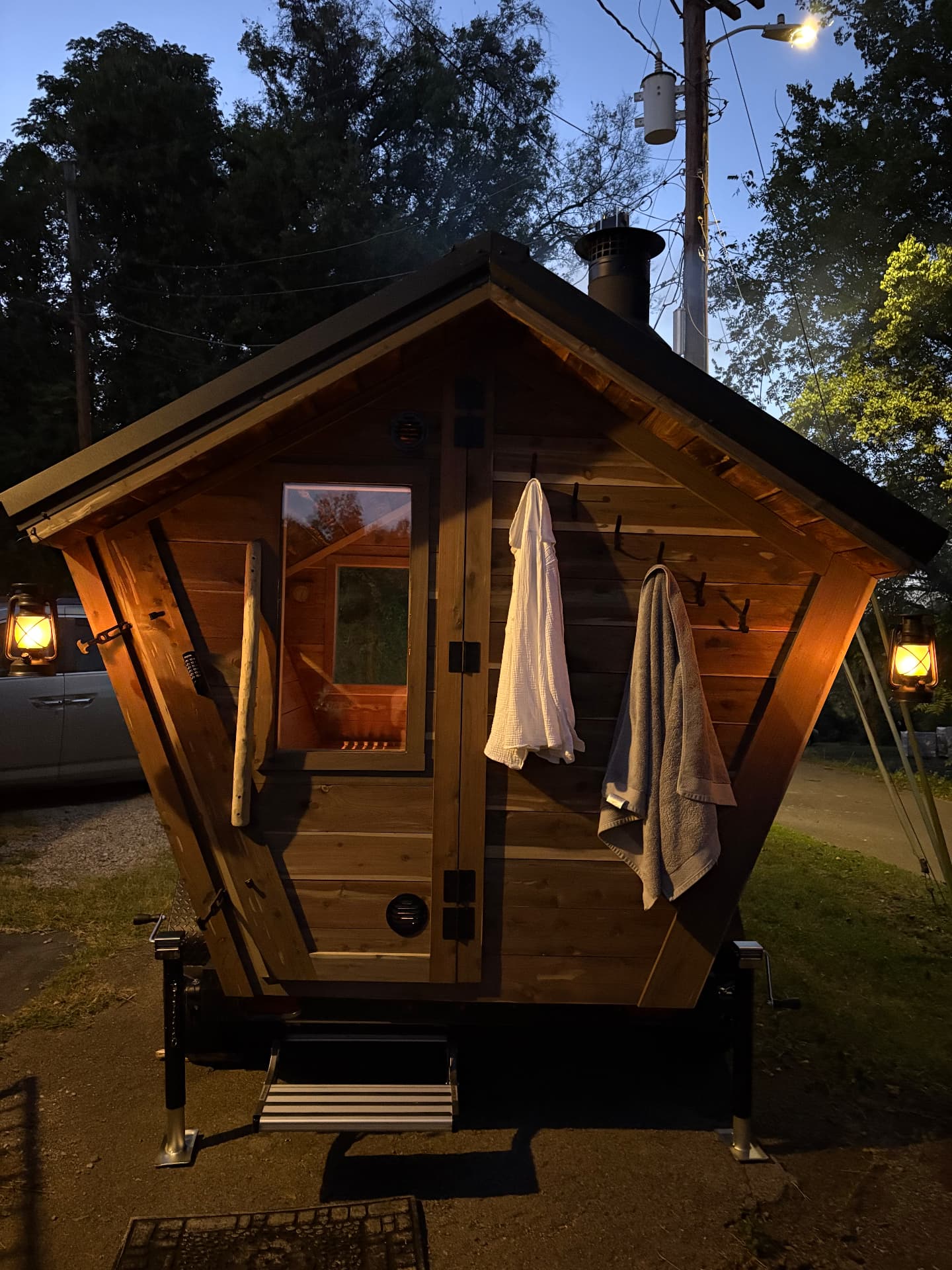The Wandering Ember wood-fired sauna glowing at dusk, towels hanging by the door